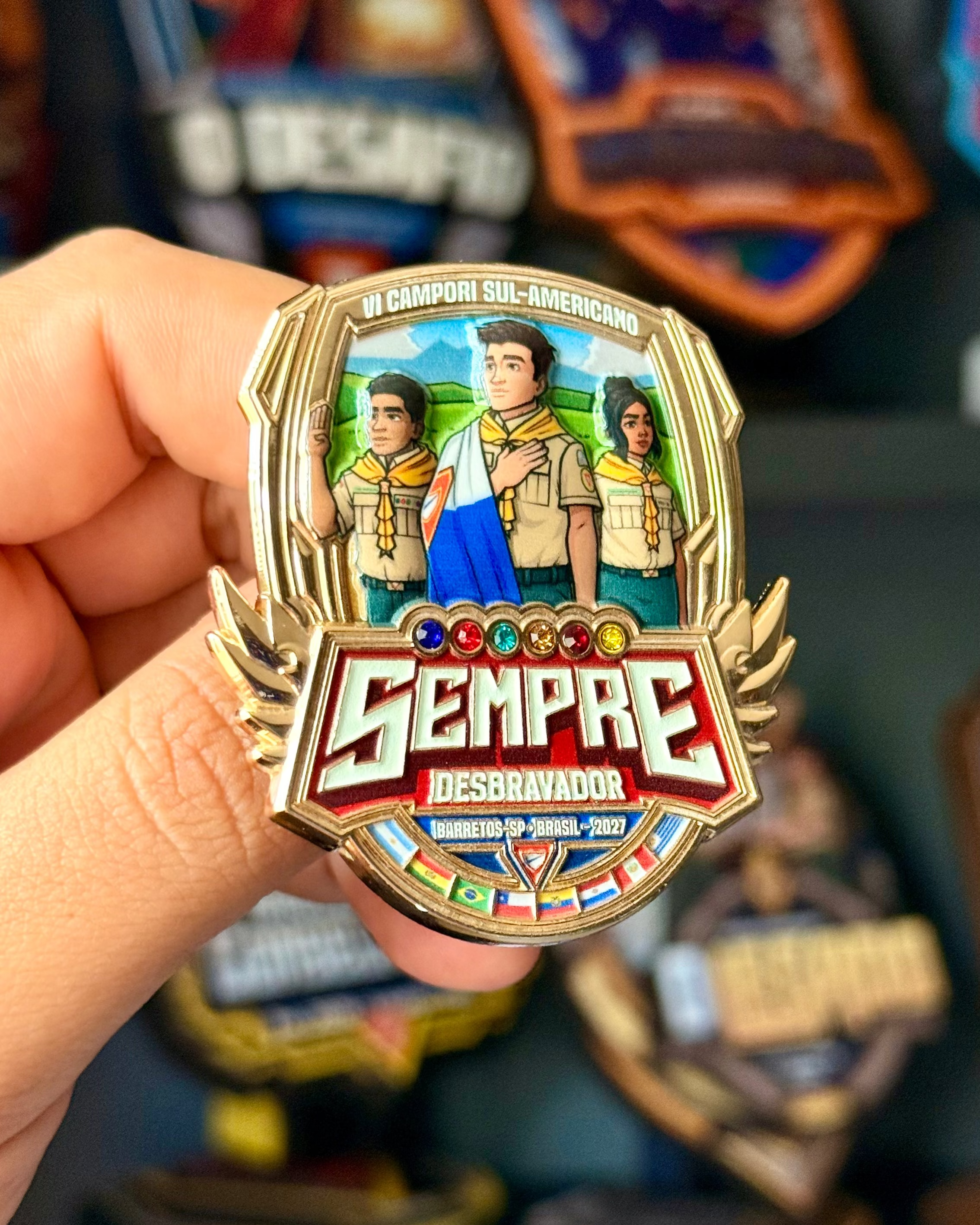 Hand holding a colorful badge with characters and 'Sempre' text against a blurred background of similar badges.